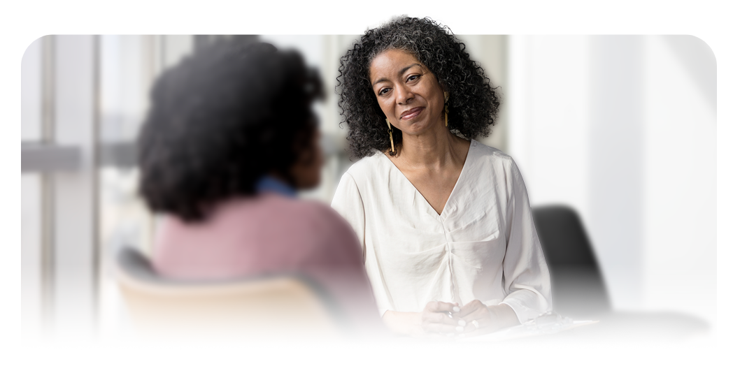 Two people seated indoors facing each other during a discussion.