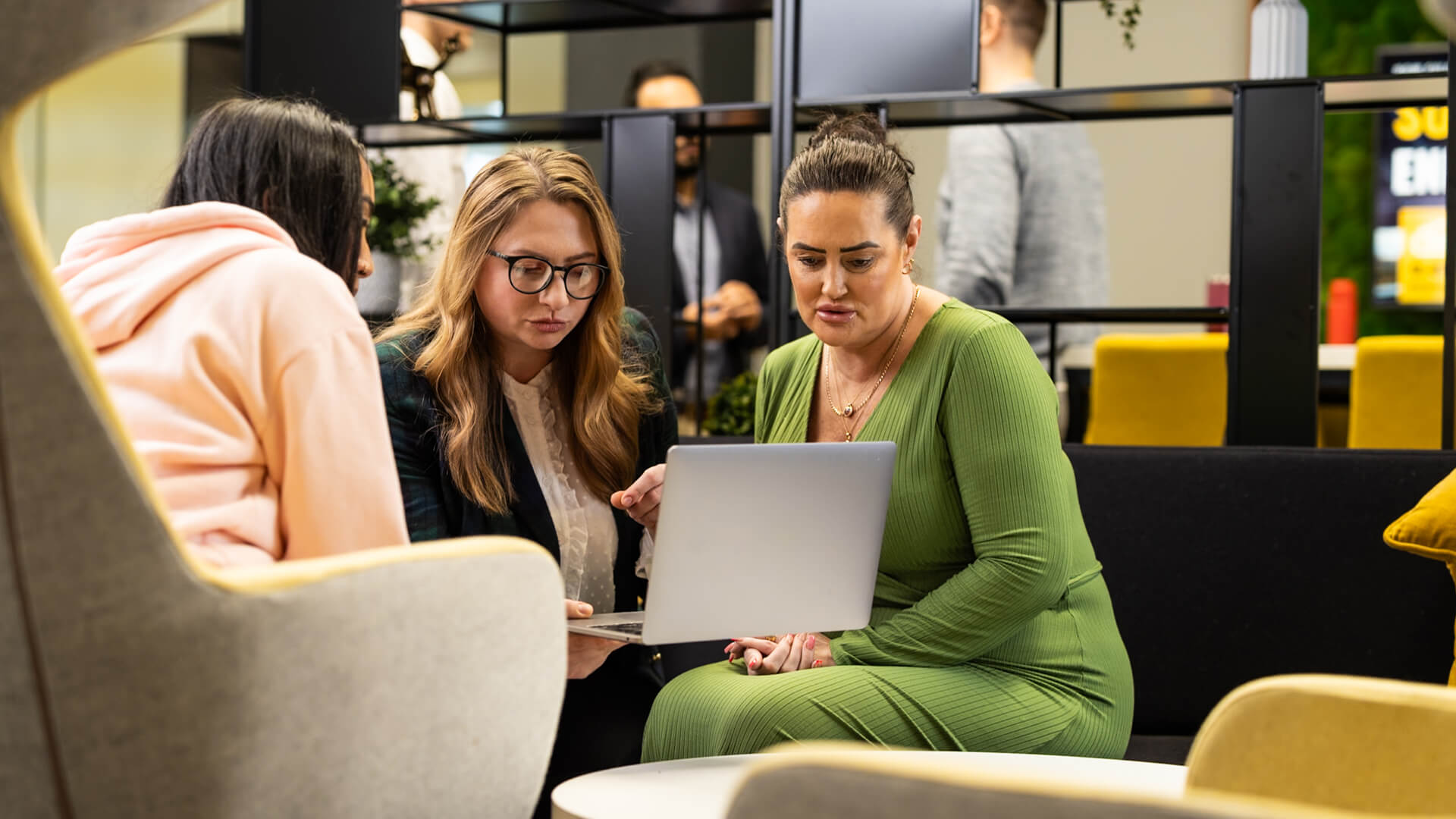 People seated in a modern workspace, reviewing information on a laptop.